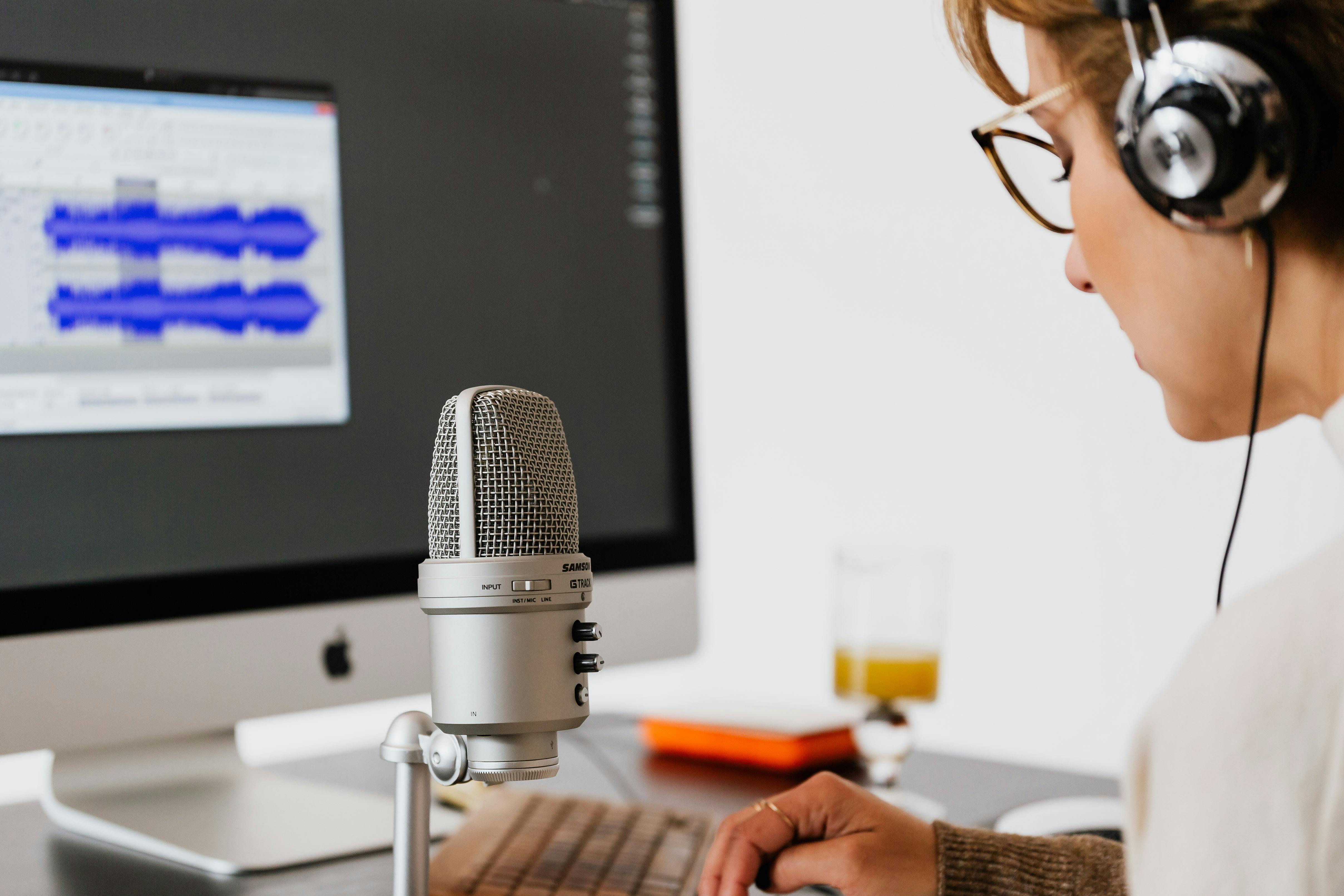 Woman sitting at a desk recording a podcast for Beehiiv.