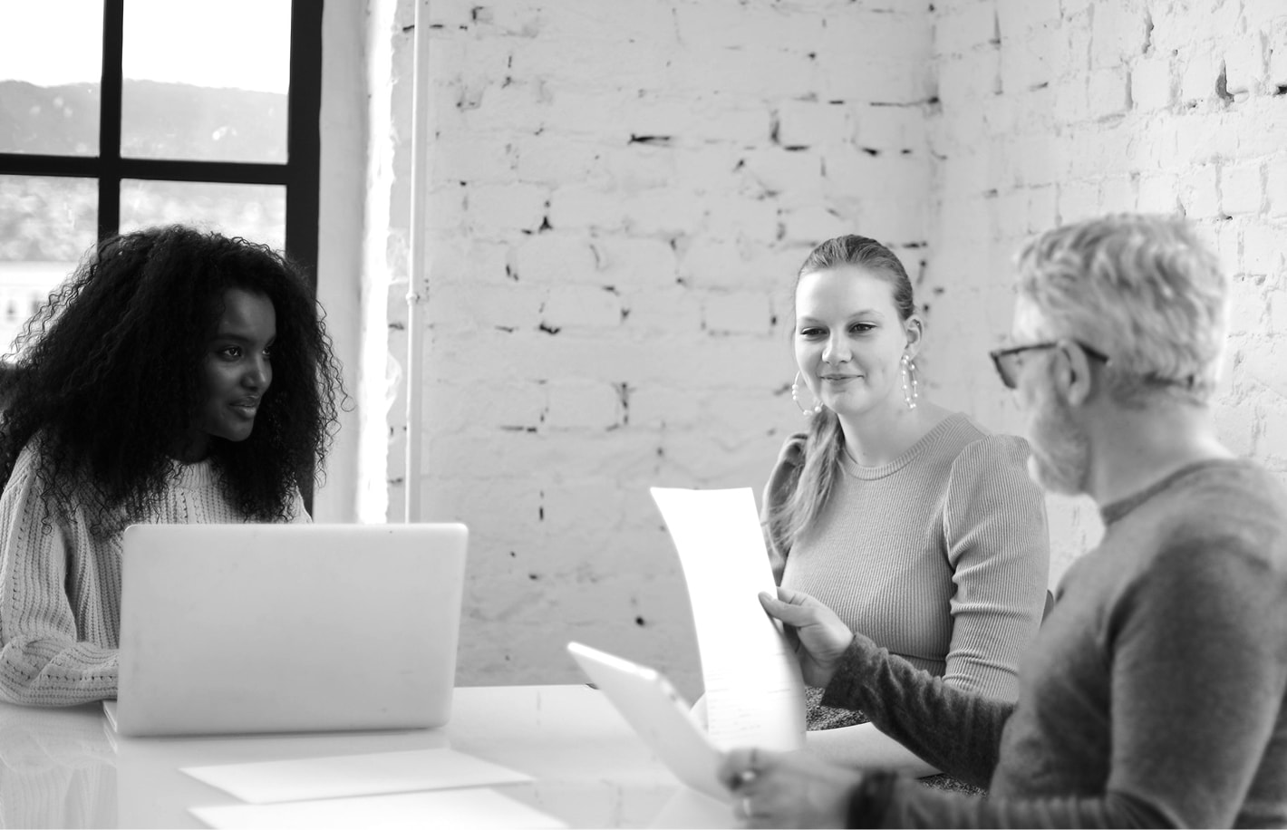 Three people sitting around a table with laptops and papers